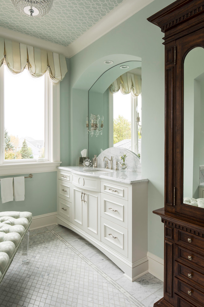Cette photo montre une salle de bain chic avec des portes de placard blanches et un mur bleu.