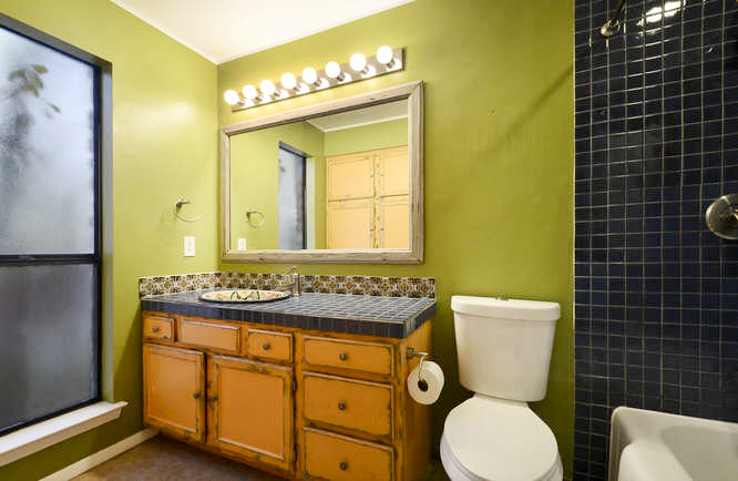 Свежая идея для дизайна: ванная комната среднего размера: освещение в стиле модернизм с плоскими фасадами, искусственно-состаренными фасадами, ванной в нише, душем над ванной, раздельным унитазом, зелеными стенами, полом из бамбука, душевой кабиной, накладной раковиной, столешницей из плитки, шторкой для ванной, разноцветной столешницей, тумбой под одну раковину, встроенной тумбой и фартуком - отличное фото интерьера