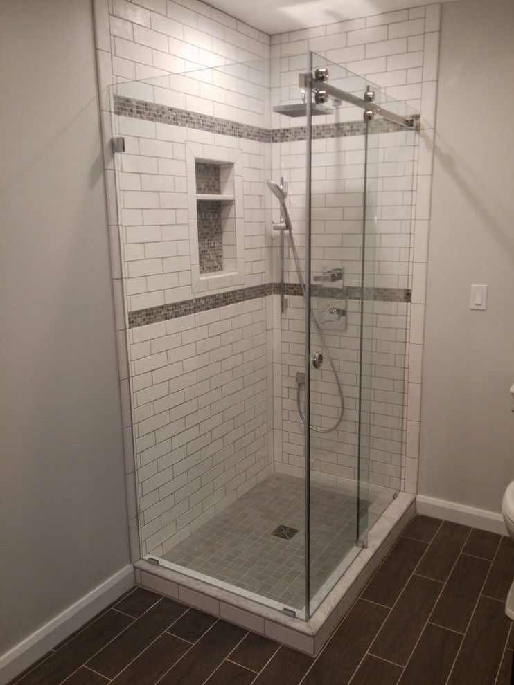 Inredning av ett amerikanskt mellanstort badrum, med en hörndusch, vit kakel, tunnelbanekakel, grå väggar, klinkergolv i porslin, brunt golv och dusch med skjutdörr
