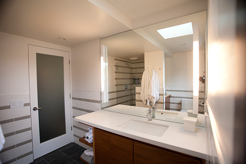 Exemple d'une salle de bain moderne avec un placard sans porte, un combiné douche/baignoire, un carrelage métro, un mur beige, un sol en ardoise et un plan de toilette en surface solide.