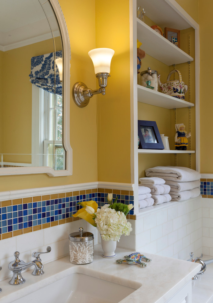 Photo of a large traditional family bathroom in New York with a submerged sink, raised-panel cabinets, white cabinets, marble worktops, a submerged bath, a corner shower, a two-piece toilet, mosaic tiles, yellow walls, ceramic flooring and blue tiles.