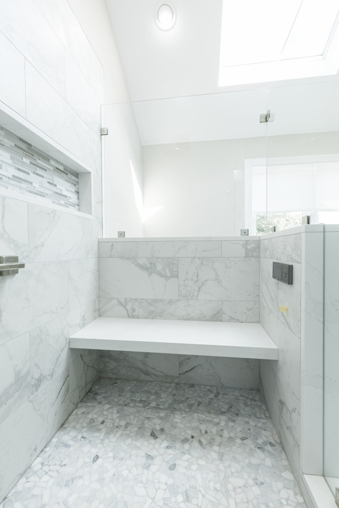 This is an example of a medium sized classic ensuite bathroom in Philadelphia with recessed-panel cabinets, grey cabinets, a corner shower, a two-piece toilet, multi-coloured tiles, glass tiles, beige walls, porcelain flooring, a submerged sink, engineered stone worktops, grey floors, a hinged door, white worktops, a shower bench, double sinks and a built in vanity unit.