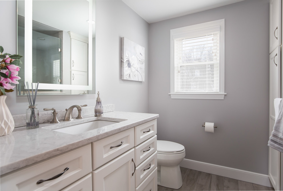 Medium sized classic ensuite bathroom in Boston with shaker cabinets, yellow cabinets, a built-in shower, a two-piece toilet, grey tiles, porcelain tiles, grey walls, porcelain flooring, a submerged sink, engineered stone worktops, grey floors and a hinged door.