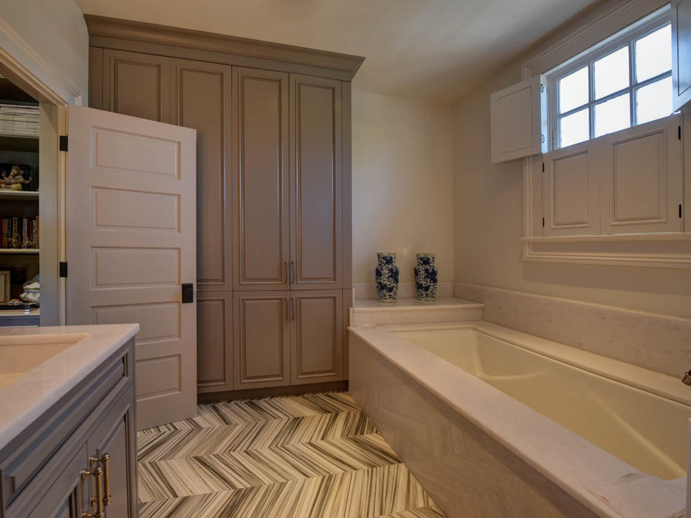 Design ideas for a large classic ensuite bathroom in New Orleans with raised-panel cabinets, grey cabinets, a submerged bath, grey walls, porcelain flooring, a submerged sink and grey floors.