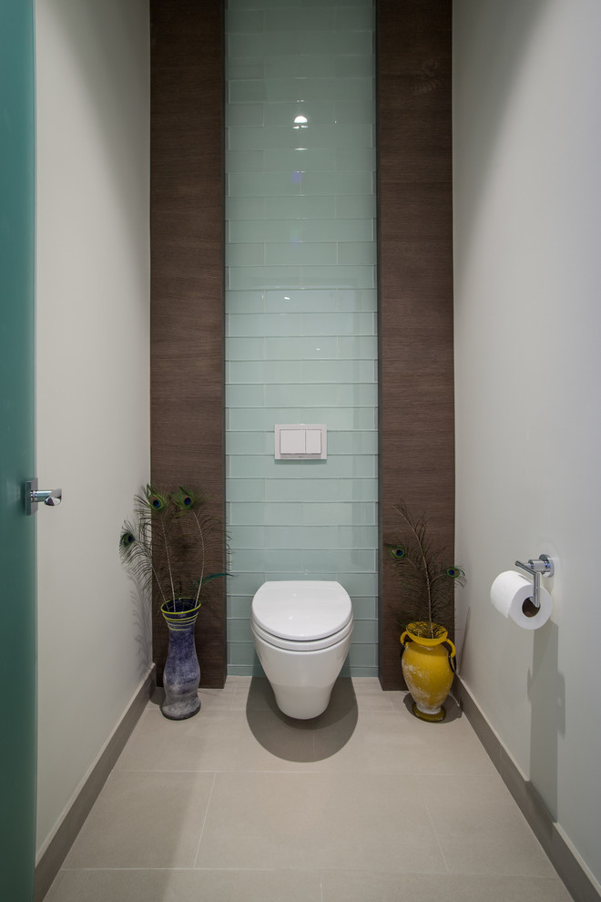 На фото: туалет в стиле модернизм с инсталляцией, синей плиткой, стеклянной плиткой, белыми стенами и полом из керамогранита
