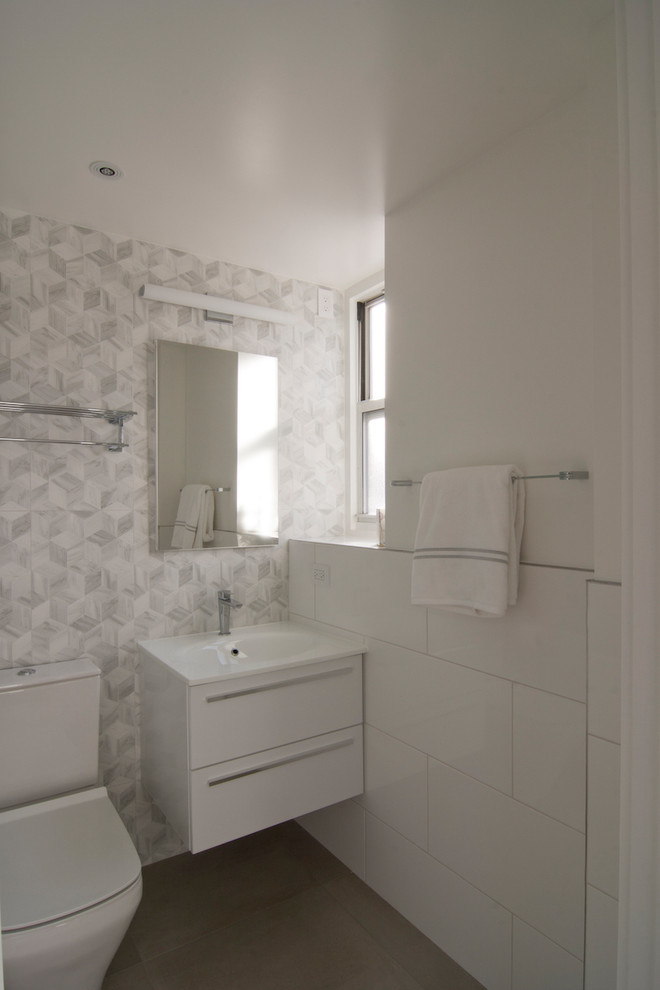 Пример оригинального дизайна: маленькая ванная комната в современном стиле с плоскими фасадами, белыми фасадами, унитазом-моноблоком, белой плиткой, керамогранитной плиткой, белыми стенами, паркетным полом среднего тона, душевой кабиной, монолитной раковиной, столешницей из кварцита и коричневым полом для на участке и в саду