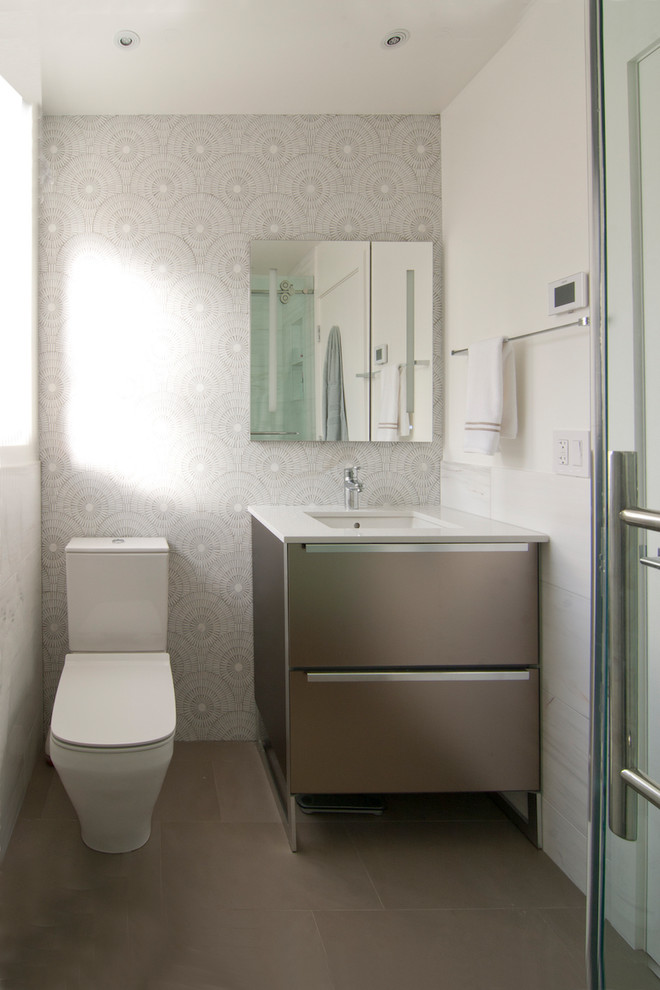 Cette image montre une salle de bain design en bois foncé avec un placard en trompe-l'oeil, WC à poser, un carrelage blanc, des carreaux de porcelaine, un mur blanc, un sol en bois brun, un lavabo encastré, un plan de toilette en quartz et un sol marron.