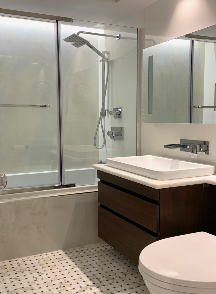 Small modern ensuite bathroom in New York with flat-panel cabinets, a built-in bath, white tiles, white walls, marble flooring and a vessel sink.