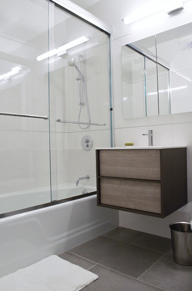 Cette photo montre une petite salle de bain principale moderne en bois clair avec un lavabo intégré, un placard à porte plane, une baignoire en alcôve, WC à poser, un carrelage gris, un carrelage de pierre, un mur marron et un sol en carrelage de porcelaine.