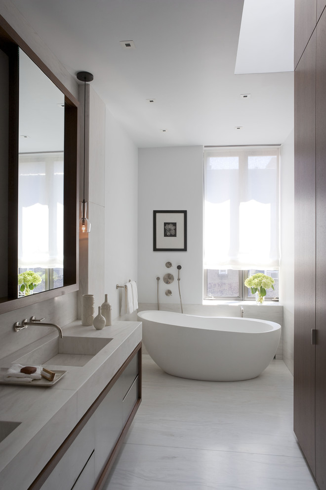 Ejemplo de cuarto de baño contemporáneo con lavabo integrado, armarios con paneles lisos, puertas de armario de madera en tonos medios y bañera exenta