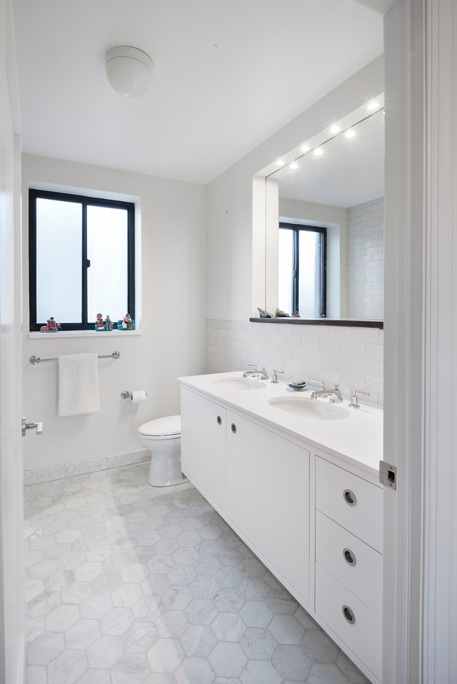 Foto de cuarto de baño contemporáneo con lavabo bajoencimera, armarios con paneles lisos, puertas de armario blancas, baldosas y/o azulejos blancos, baldosas y/o azulejos de cemento y paredes blancas