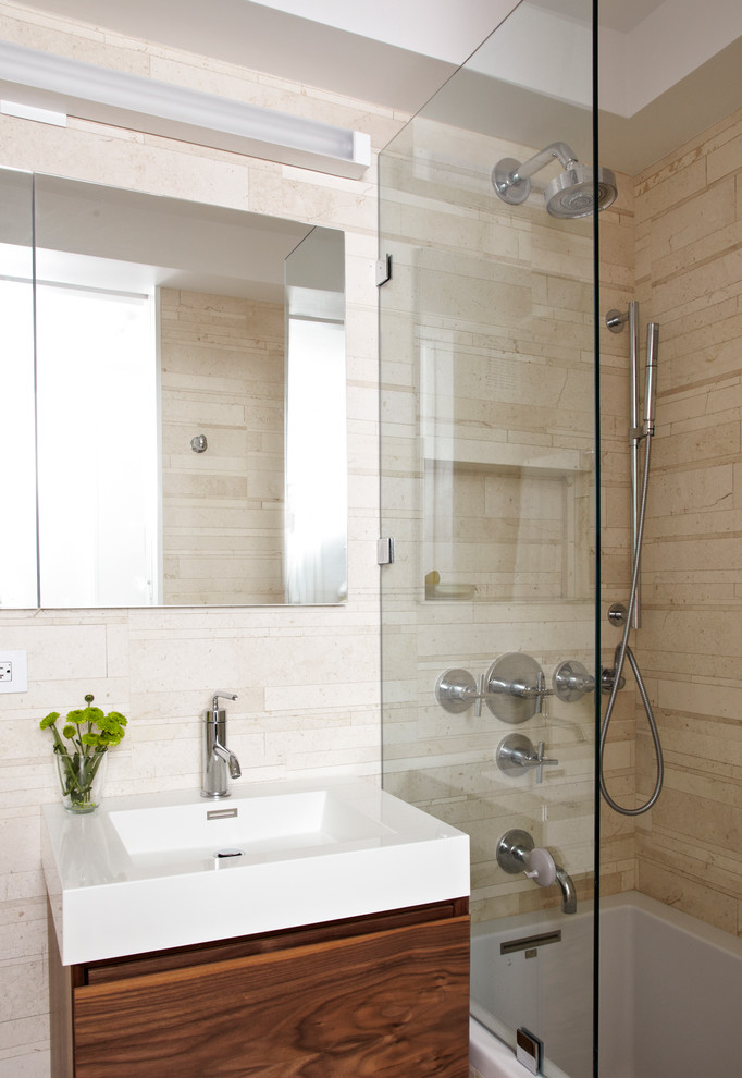 Immagine di una stanza da bagno design con lavabo integrato e piastrelle di pietra calcarea
