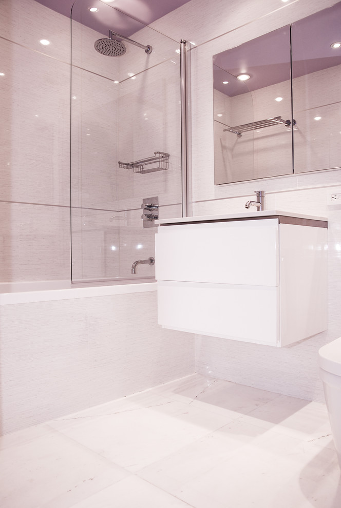 Immagine di una stanza da bagno minimalista con lavabo sottopiano, ante bianche, top in quarzo composito, vasca ad alcova, vasca/doccia, WC monopezzo, piastrelle bianche e piastrelle in gres porcellanato