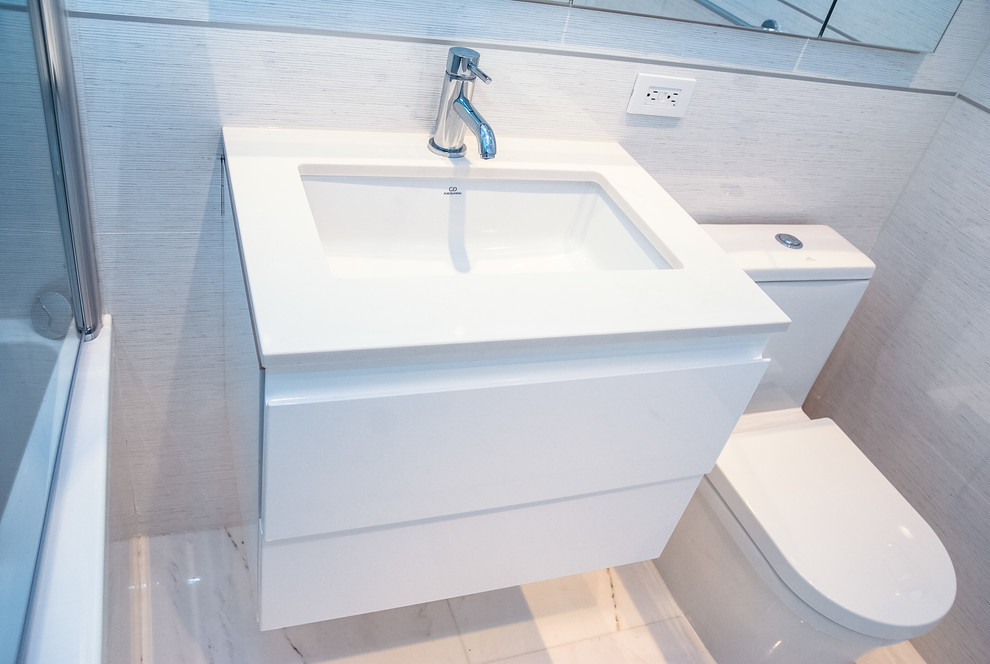 Photo of a modern bathroom in New York with a submerged sink, white cabinets, engineered stone worktops, a built-in bath, a shower/bath combination, a one-piece toilet, white tiles and porcelain tiles.