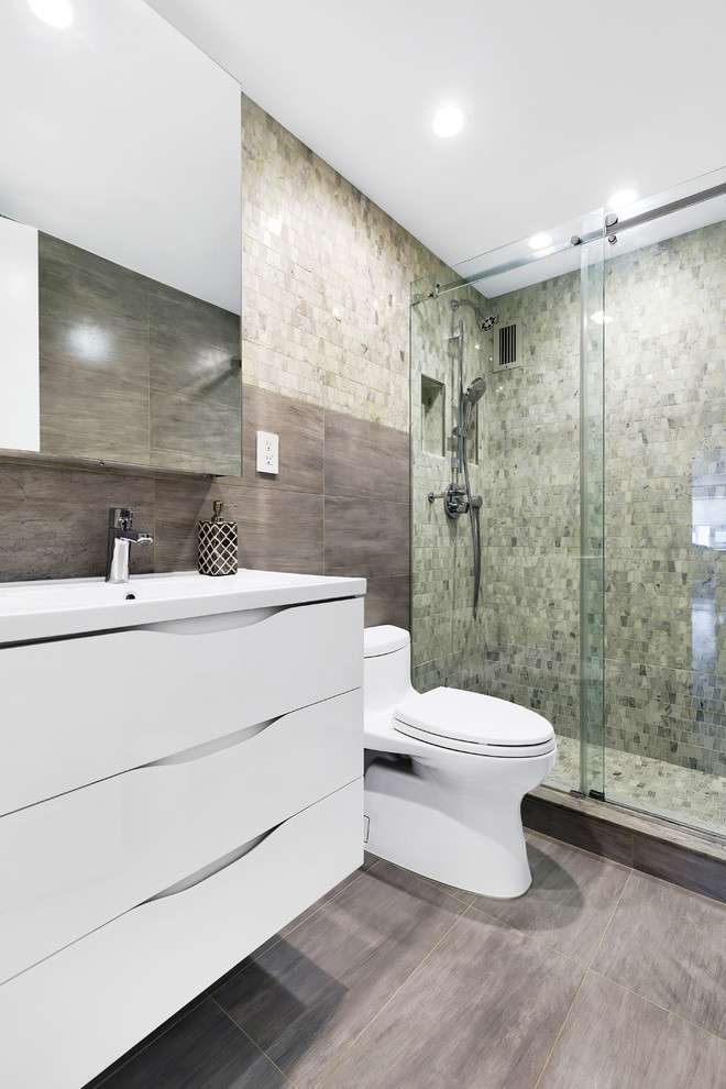 Cette image montre une salle de bain design avec des portes de placard noires, WC à poser, un carrelage gris, un plan vasque, un sol gris et une cabine de douche à porte coulissante.
