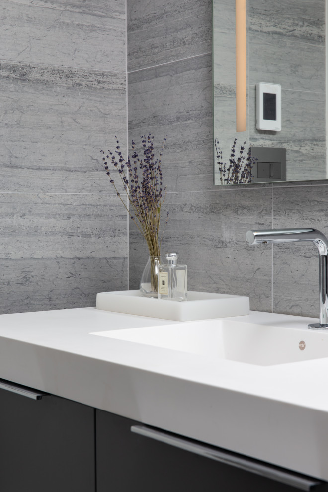 This is an example of a medium sized contemporary bathroom in New York with freestanding cabinets, grey cabinets, a walk-in shower, grey tiles, marble tiles, grey walls, marble flooring, a wall-mounted sink, grey floors, an open shower, white worktops, a single sink and a floating vanity unit.