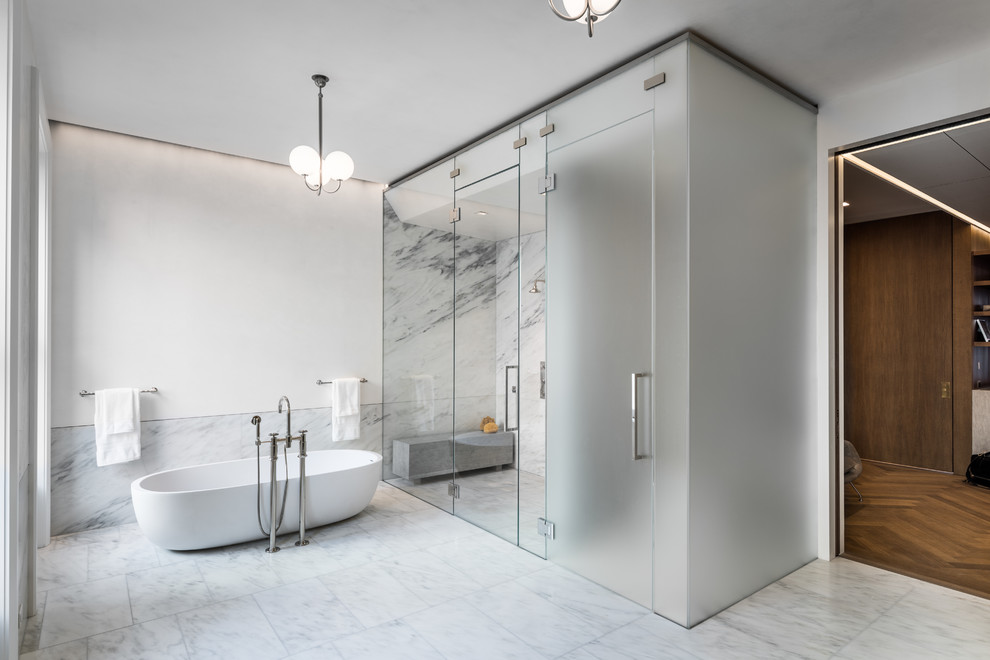 Réalisation d'une très grande salle de bain principale minimaliste avec une baignoire indépendante, une douche double, des dalles de pierre, un mur blanc, un plan de toilette en marbre, une cabine de douche à porte battante et un plan de toilette blanc.