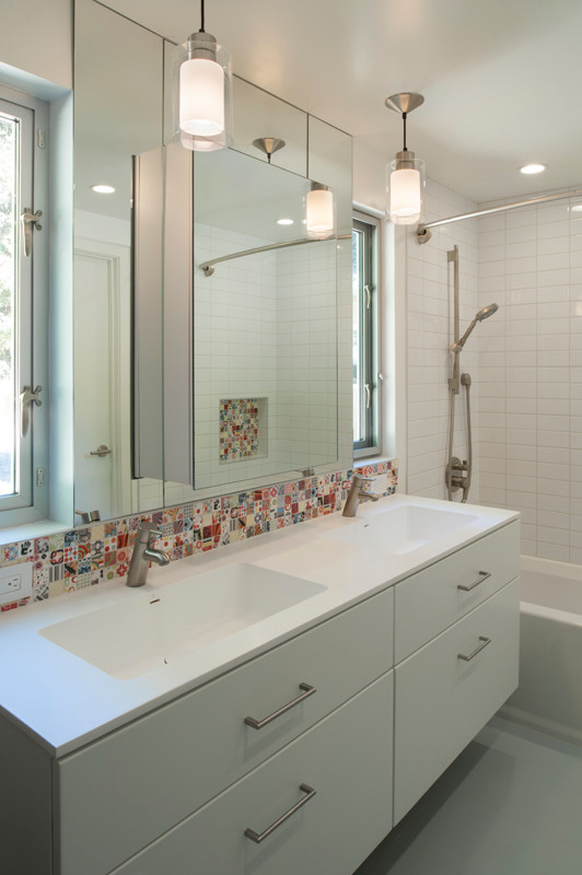 This is an example of a modern bathroom in San Francisco with an integrated sink, flat-panel cabinets, white cabinets, an alcove bath, a shower/bath combination, white tiles, ceramic tiles and white walls.