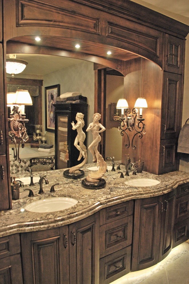 Klassisk inredning av ett stort en-suite badrum, med ett undermonterad handfat, möbel-liknande, skåp i mellenmörkt trä, granitbänkskiva och ett platsbyggt badkar