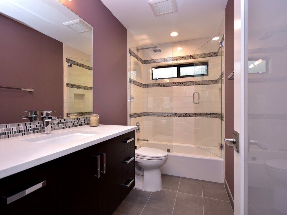 Modern inredning av ett mellanstort badrum med dusch, med släta luckor, en dusch/badkar-kombination, mosaik, lila väggar, ett undermonterad handfat, svarta skåp, en toalettstol med separat cisternkåpa, svart och vit kakel, grå kakel, skiffergolv och bänkskiva i kvartsit