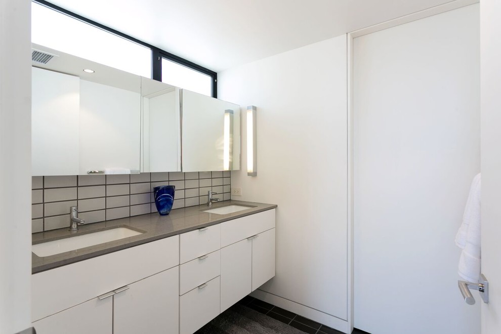 Minimalist 3/4 white tile and subway tile black floor bathroom photo in San Francisco with flat-panel cabinets, white cabinets, white walls and an undermount sink