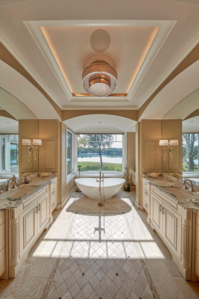 Esempio di una stanza da bagno padronale classica di medie dimensioni con consolle stile comò, ante bianche, vasca freestanding, piastrelle beige, pavimento con piastrelle in ceramica, lavabo sottopiano, top in granito e pavimento beige