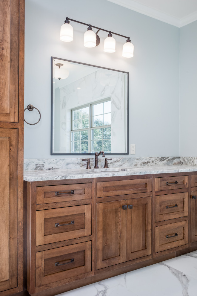 Photo of a large rural ensuite bathroom in Austin with shaker cabinets, brown cabinets, a claw-foot bath, a built-in shower, a one-piece toilet, white tiles, porcelain tiles, blue walls, porcelain flooring, a submerged sink, granite worktops, white floors, an open shower and brown worktops.