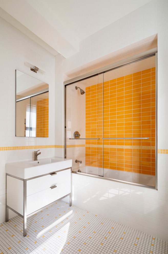 Aménagement d'une salle de bain contemporaine avec un placard à porte plane, des portes de placard blanches, une baignoire en alcôve, un combiné douche/baignoire, un carrelage jaune, un mur multicolore, un lavabo intégré, un sol multicolore et une cabine de douche à porte coulissante.