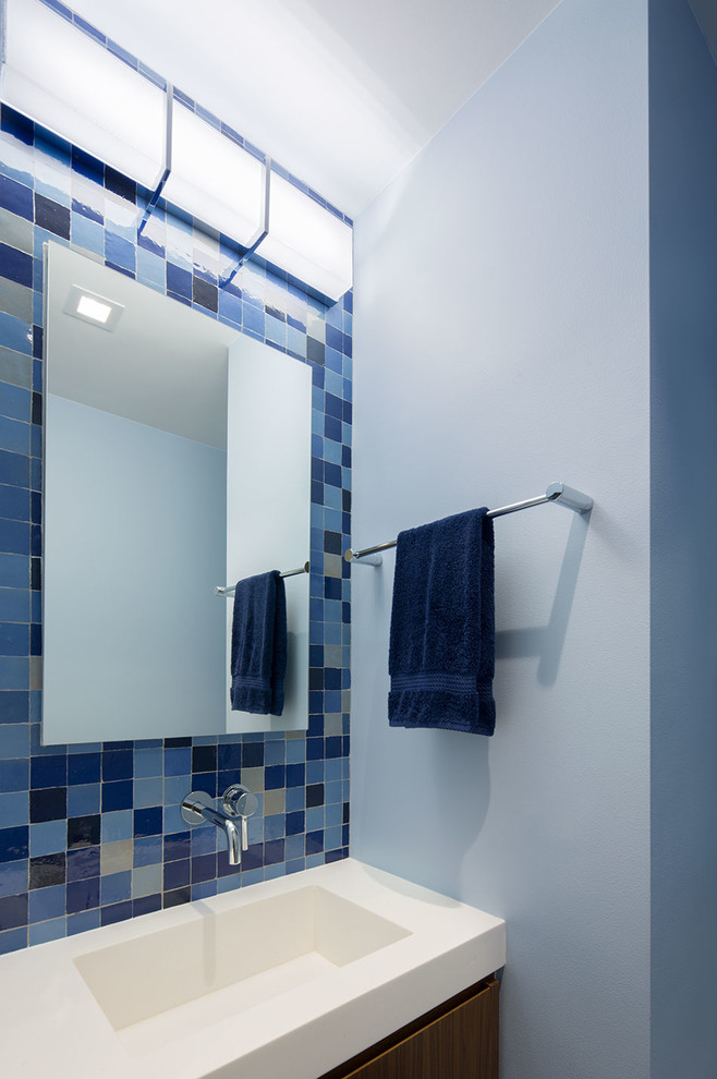 Idéer för att renovera ett litet funkis vit vitt badrum för barn, med släta luckor, skåp i mellenmörkt trä, en hörndusch, en toalettstol med hel cisternkåpa, tunnelbanekakel, blå väggar, klinkergolv i keramik, flerfärgat golv, dusch med gångjärnsdörr, blå kakel och bänkskiva i akrylsten