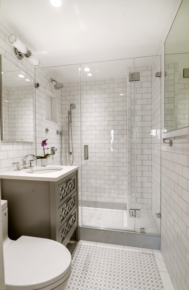 ニューヨークにある高級な小さなトランジショナルスタイルのおしゃれなマスターバスルーム (グレーのキャビネット、アルコーブ型シャワー、一体型トイレ	、白いタイル、白い壁、アンダーカウンター洗面器、サブウェイタイル、モザイクタイル、クオーツストーンの洗面台、落し込みパネル扉のキャビネット) の写真