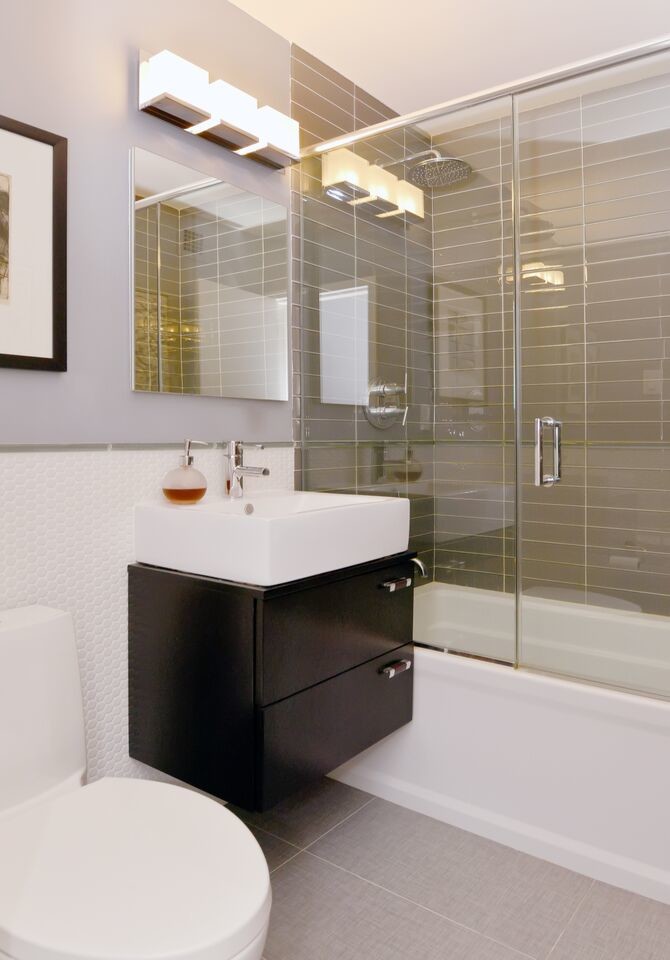 Small contemporary bathroom in Miami with a console sink, flat-panel cabinets, dark wood cabinets, an alcove bath, a shower/bath combination, a one-piece toilet, grey tiles, glass tiles, grey walls and porcelain flooring.
