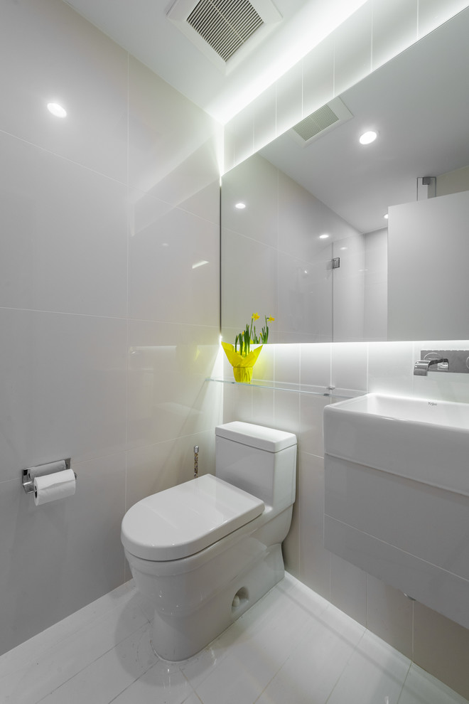 Пример оригинального дизайна: маленькая ванная комната в стиле модернизм с угловым душем, унитазом-моноблоком, белой плиткой, стеклянной плиткой, белыми стенами, полом из керамогранита, душевой кабиной, плоскими фасадами, белыми фасадами, монолитной раковиной и белым полом для на участке и в саду