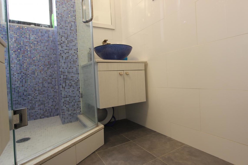 Small trendy 3/4 blue tile and mosaic tile ceramic tile corner shower photo in New York with a vessel sink, flat-panel cabinets, white cabinets, quartz countertops, white walls and a one-piece toilet