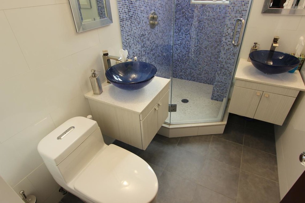 Kleines Modernes Duschbad mit Aufsatzwaschbecken, flächenbündigen Schrankfronten, weißen Schränken, Quarzwerkstein-Waschtisch, Eckdusche, blauen Fliesen, Mosaikfliesen, weißer Wandfarbe, Toilette mit Aufsatzspülkasten und Keramikboden in New York