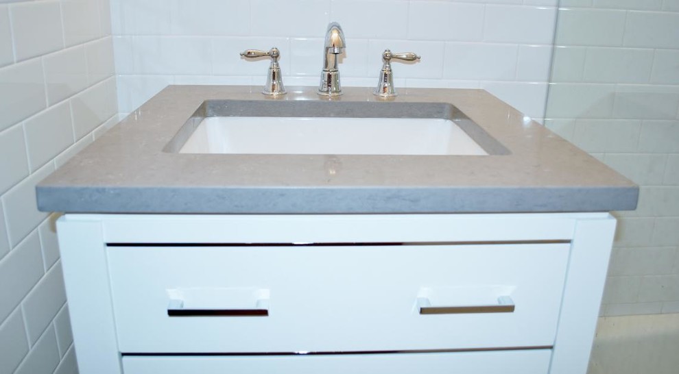 Bild på ett litet vintage badrum med dusch, med ett undermonterad handfat, släta luckor, vita skåp, bänkskiva i täljsten, en hörndusch, vit kakel, tunnelbanekakel, vita väggar och marmorgolv