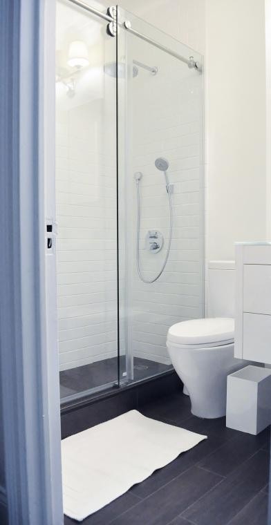 Small minimalist 3/4 white tile and subway tile vinyl floor corner shower photo in New York with a wall-mount sink, flat-panel cabinets, white cabinets, white walls and a two-piece toilet