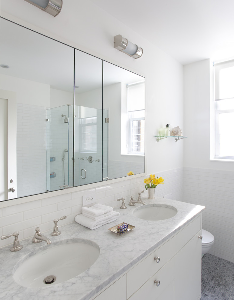 Inspiration for a mid-sized contemporary 3/4 subway tile mosaic tile floor and gray floor corner shower remodel in New York with marble countertops, flat-panel cabinets, white cabinets, white walls, an undermount sink and a hinged shower door