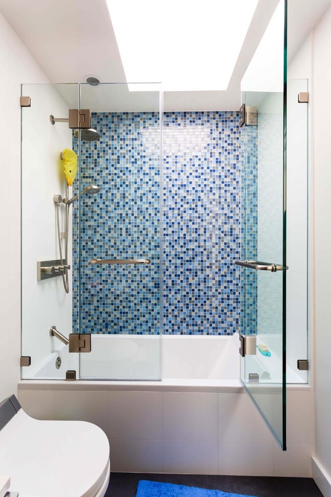 Modelo de cuarto de baño clásico renovado de tamaño medio con sanitario de una pieza, paredes blancas, bañera empotrada, ducha empotrada, baldosas y/o azulejos azules, baldosas y/o azulejos en mosaico, aseo y ducha y ducha con puerta con bisagras