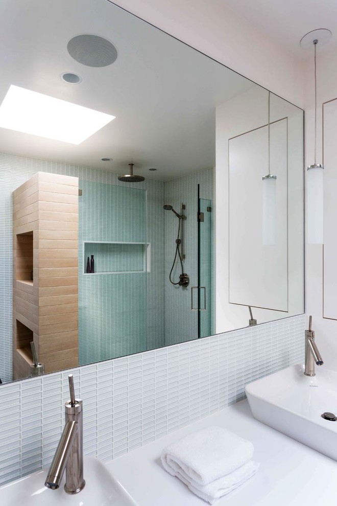 Medium sized modern ensuite bathroom in New York with white cabinets, an alcove shower, green tiles, glass tiles, white walls, a vessel sink and solid surface worktops.