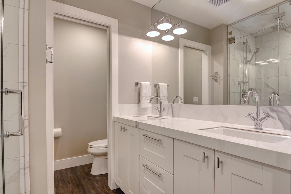 Inredning av ett klassiskt litet badrum, med släta luckor, vita skåp, en öppen dusch, en toalettstol med hel cisternkåpa, vit kakel, beige väggar och mörkt trägolv