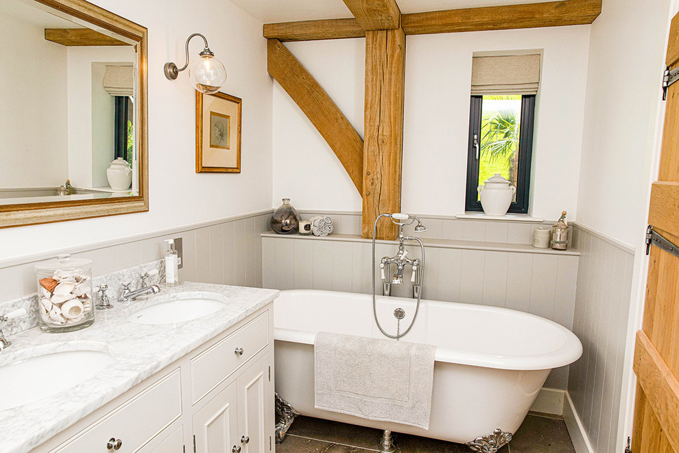 Country Badezimmer En Suite mit Schrankfronten mit vertiefter Füllung, weißen Schränken, Löwenfuß-Badewanne, weißer Wandfarbe, Unterbauwaschbecken und weißer Waschtischplatte in Wiltshire