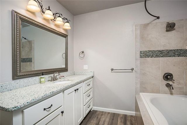 Klassisk inredning av ett litet badrum, med skåp i shakerstil, vita skåp, ett platsbyggt badkar, en dusch/badkar-kombination, beige kakel, porslinskakel, grå väggar, mellanmörkt trägolv, ett undermonterad handfat, bänkskiva i terrazo, beiget golv och dusch med duschdraperi