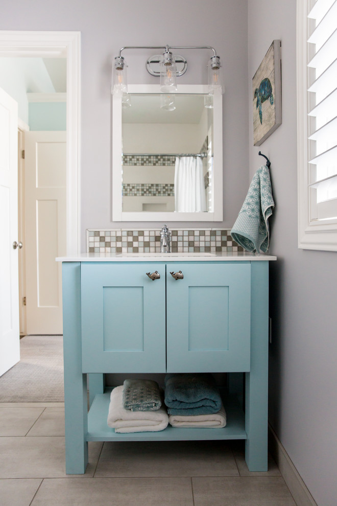 На фото: большая детская ванная комната в морском стиле с фасадами в стиле шейкер, синими фасадами, ванной в нише, угловым душем, раздельным унитазом, разноцветной плиткой, плиткой мозаикой, серыми стенами, полом из керамогранита, монолитной раковиной, столешницей из искусственного камня, серым полом, душем с распашными дверями и белой столешницей с