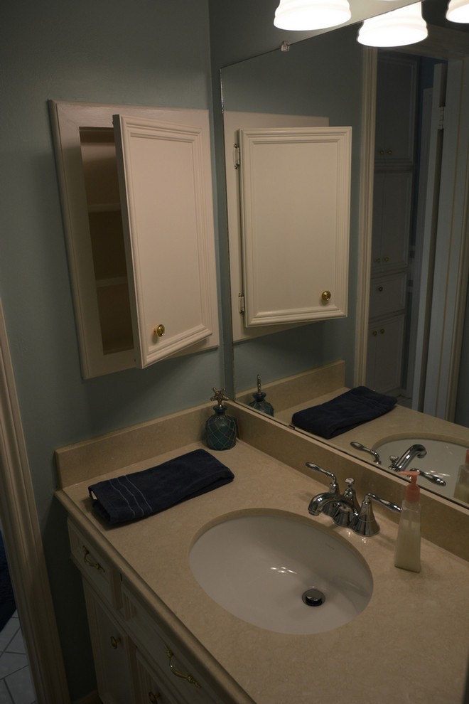 Réalisation d'une salle de bain marine de taille moyenne avec des portes de placard blanches, un plan de toilette en quartz modifié, un carrelage blanc et un mur bleu.