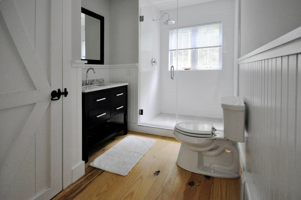 Mid-sized transitional 3/4 gray tile and subway tile light wood floor alcove shower photo in New York with an integrated sink, flat-panel cabinets, dark wood cabinets, marble countertops, a one-piece toilet and gray walls