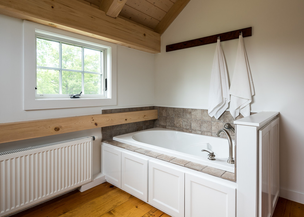 Cette photo montre une salle de bain principale nature de taille moyenne avec un placard avec porte à panneau encastré, des portes de placard blanches, un bain bouillonnant, un mur blanc, parquet clair, un plan de toilette en bois et un sol jaune.