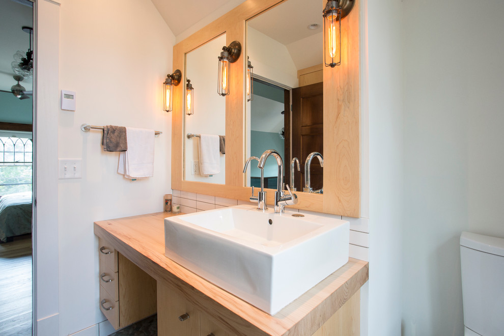Bild på ett mellanstort funkis badrum med dusch, med släta luckor, skåp i ljust trä, en dusch i en alkov, vit kakel, keramikplattor, ett fristående handfat, träbänkskiva, vita väggar och klinkergolv i småsten