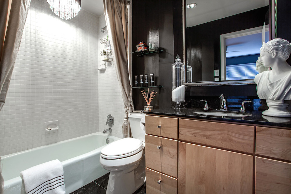 This is an example of a medium sized eclectic ensuite bathroom in Dallas with a submerged sink, flat-panel cabinets, light wood cabinets, granite worktops, an alcove bath, a shower/bath combination, a one-piece toilet, white tiles, metro tiles, black walls and marble flooring.