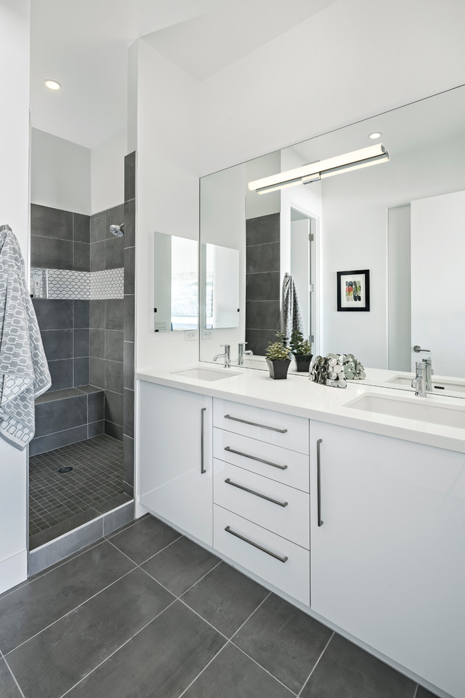 Modern inredning av ett mellanstort en-suite badrum, med släta luckor, vita skåp, en dusch i en alkov, en toalettstol med separat cisternkåpa, grå kakel, porslinskakel, vita väggar, klinkergolv i porslin och bänkskiva i kvarts