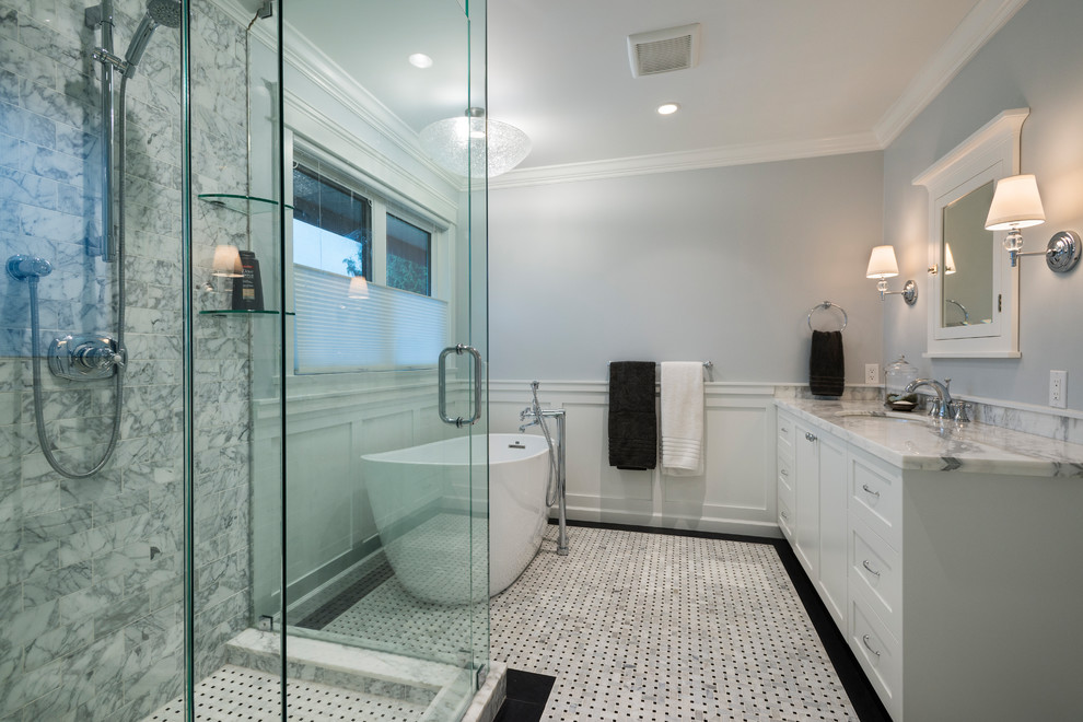 Inspiration for a large traditional ensuite bathroom in Vancouver with raised-panel cabinets, white cabinets, a freestanding bath, a walk-in shower, a two-piece toilet, grey tiles, marble tiles, grey walls, porcelain flooring, a submerged sink, marble worktops, white floors and a hinged door.